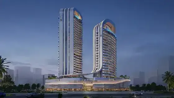 Radisson Blu Hotel and Residences twin towers illuminated at dusk in RAK Central